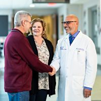 Healthcare professionals and patients interact warmly in a hospital hallway, highlighting patient-centered care.